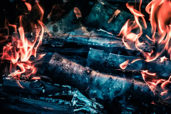 Bright hot coals and burning woods in bbq grill pit. Glowing and flaming charcoal, barbecue, red fire and ash. Weekend recreation background. Close-up, top view.