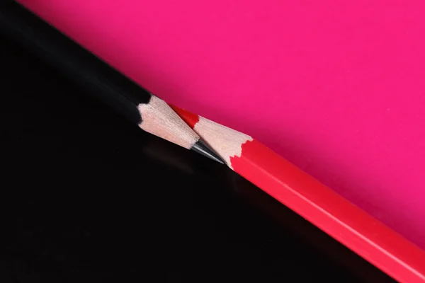 用紙の背景に分離した赤と黒の色鉛筆 — ストック写真