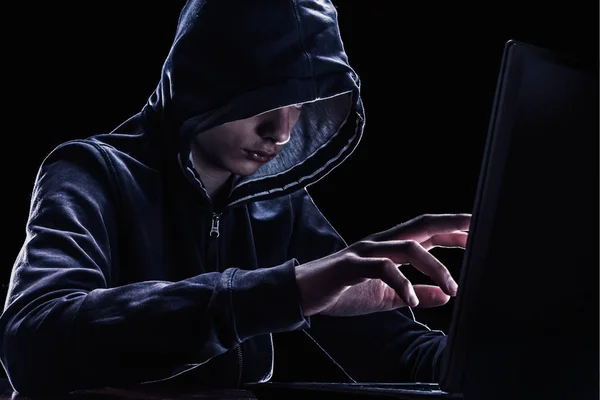 Violation of intellectual property rights concept. Hacker in a hood on black background.