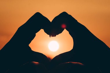 Siluet el Paz gök, aşk sembolü, günbatımı veya şafak üzerinde kalp şeklinde