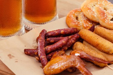 Kanatları ve bira bardağı masada Alman yemekleri tuzlu kraker mısırlı sosis füme.