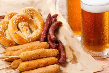Alman Milli yemekleri tuzlu kraker, sosisli sandviç ve bira oktoberfest ahşap masanın üstüne kupa.