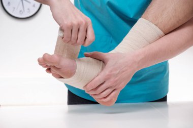 Kadın doktor erkek hastanın doktorun ofisindeki ayak bandaj Close-Up.