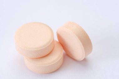 Beyaz arka plan makrosu üzerinde izole edilmiş pembe haplar ve haplar