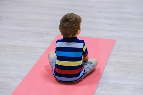 caucasian kid exercising on yoga mats in gym, children sport school