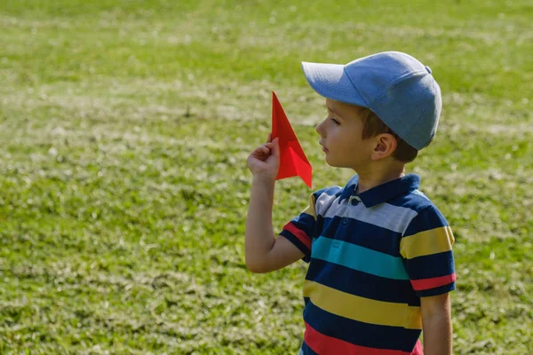 日当たりの良い夏の日の公園で赤いおもちゃの飛行機と遊ぶ少年 — ストック写真