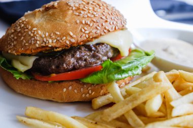 Hamburger ve patates kızartması masada beyaz tabakta..