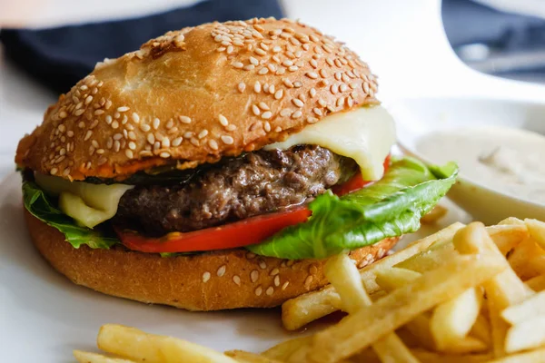 Hamburger ve patates kızartması masada beyaz tabakta..