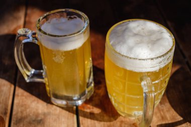 Yakın çekim iki soğuk bira köpük ve su ile damla eski ahşap tablo güneş ışını ile açık