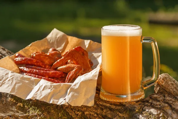 Octoberfest mug beer with traditional food on nature background.