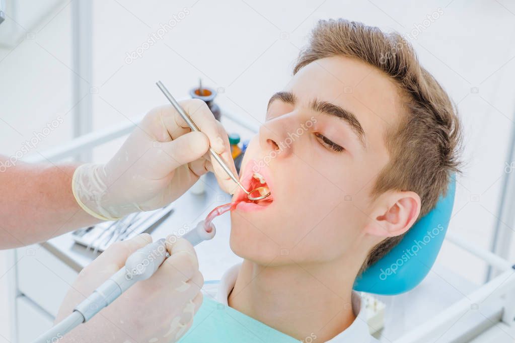 Dental caries prevention.Teenage boy at the dentist's chair during a dental procedure, smile close up. Healthy Smile.