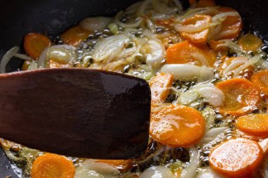 Soğan ve havuç Pan spatula ile kızartma, kızartma.