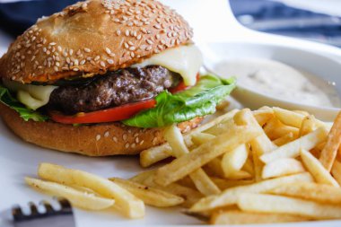 Hamburger ve kızarmış patates beyaz plaka.