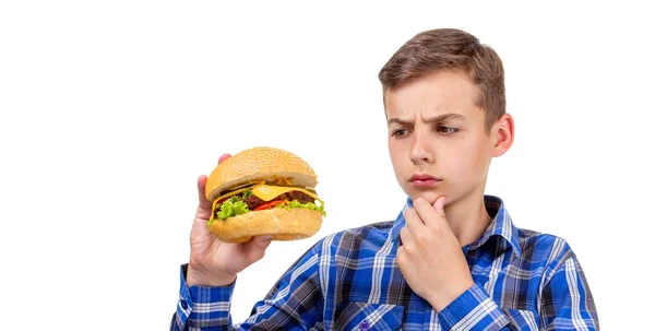 Caucasiano menino comer hambúrguer e hambúrguer no fundo branco, carne . — Fotografia de Stock