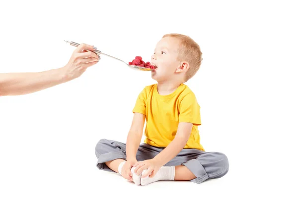 Niño pequeño está comiendo frambuesas, aislado sobre blanco — Foto de Stock