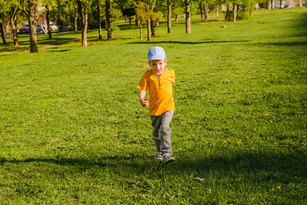 Lindo chico corriendo a través de hierba und sonriendo . — Foto de Stock