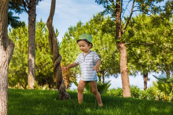 Jongen op groene gras gazon in zomerpark, weinig. — Stockfoto