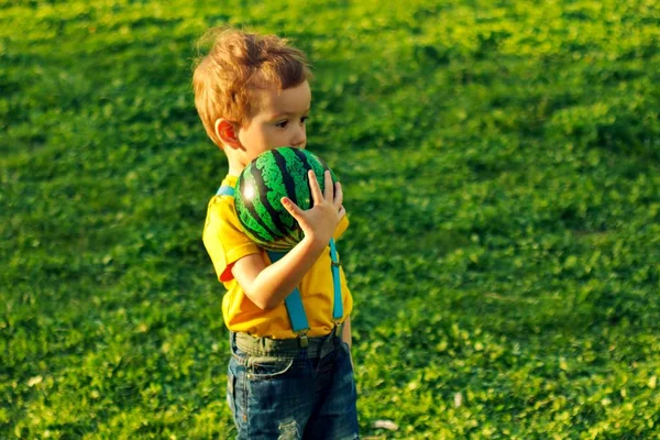 Хлопчик на зеленому газоні в літньому парку, кавказький . — стокове фото