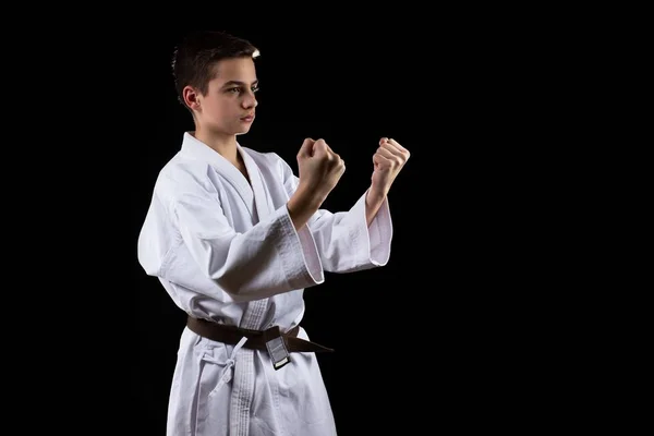 Karate harci sport fiatal fiú kimonó, fekete háttér, gyakorlat. — Stock Fotó