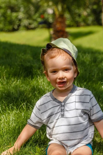 Pojke på grön gräsmatta i sommarpark, utanför. — Stockfoto