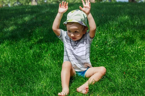 Niño en césped de hierba verde en el parque de verano, niño . —  Fotos de Stock