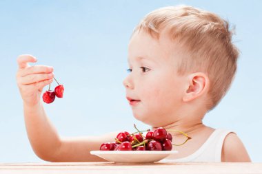Kırmızı meyveler ile çocuk, çocuk yiyor ve kiraz seçer.