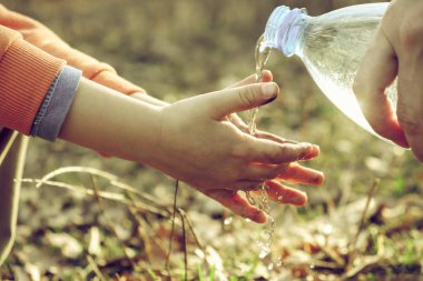 Küçük bir çocuk annesi ile pikniğe ellerini yıkar. Yemeden önce açık hijyen