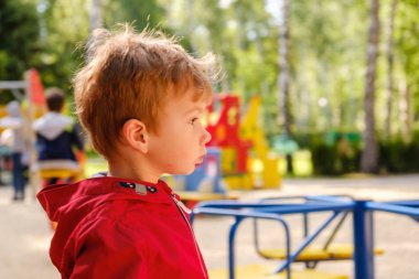 Parkta oyun alanı atlıkarıncasında oynayan çocuk