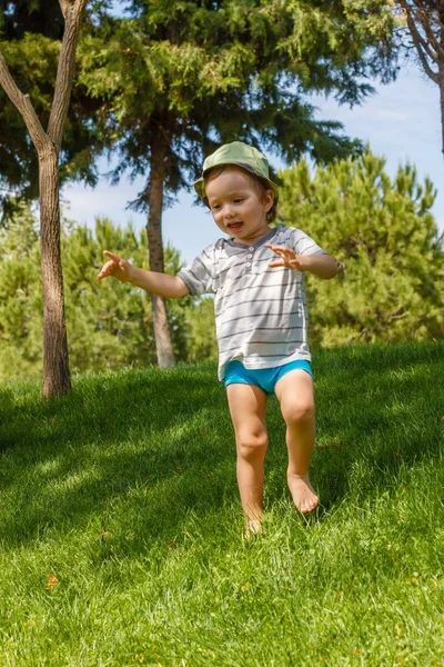 Niño en césped de hierba verde en el parque de verano, la naturaleza . — Foto de Stock