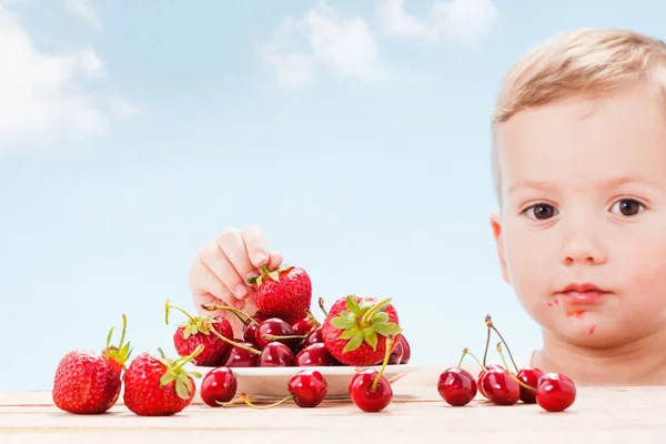 Bambino con bacche rosse, ragazzo mangia e sceglie ciliegia . — Foto Stock