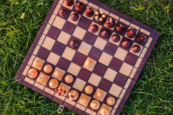Szachownica i szachy sztuk na trawie w ogrodzie — Zdjęcie stockowe
