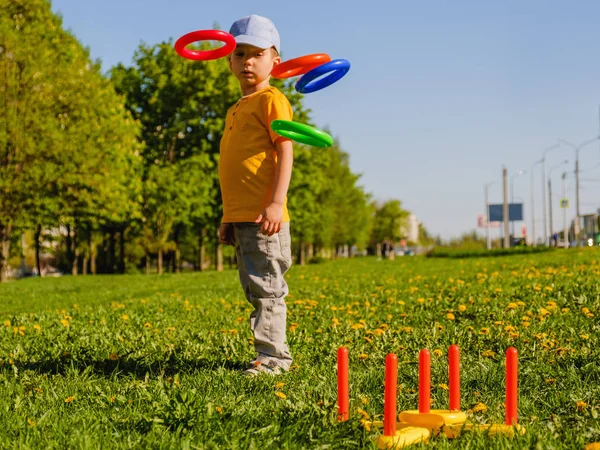 Niño jugando. Anillo de lanzar juego de verano en un césped verde en el sol —  Fotos de Stock