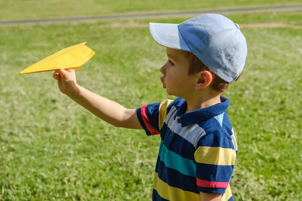 Jongen spelen met een gele speelgoed vliegtuig in Park op een zonnige dag — Stockfoto