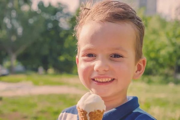 Piccolo ragazzo caucasico godendo di un gelato sciogliente in un soffocante caldo giorno d'estate. Alberi estivi verdi sullo sfondo — Foto Stock