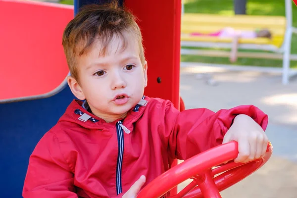 Menino jogando no parque infantil carro carrossel no parque de diversões — Fotografia de Stock