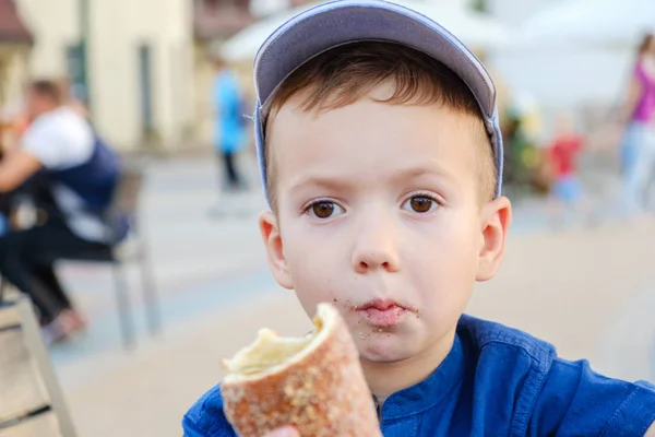 Comer o rolo é um verdadeiro prazer para o menino. Fim de semana, criança no parque . — Fotografia de Stock