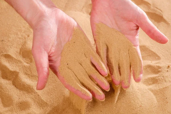Primer plano de la mano femenina soltando arena. Arena fluyendo a través de las manos . — Foto de Stock