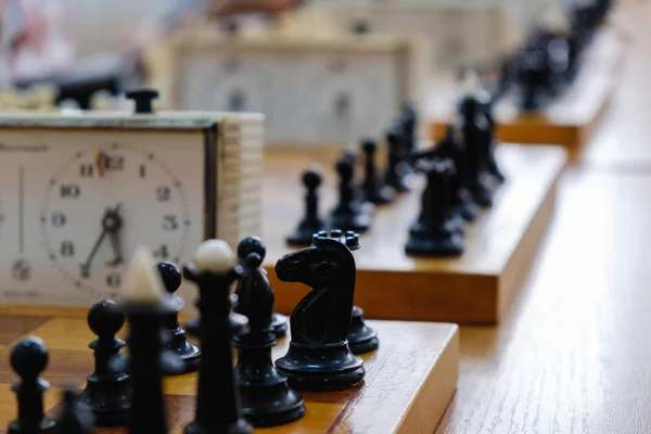Schaakbord met stukken en klok op houten bureau in het kader van het chess-toernooi. — Stockfoto