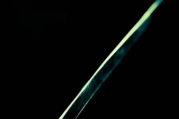 Rayo de luz estrecho en la hoja de un cuchillo de acero sobre un fondo abstracto negro —  Fotos de Stock