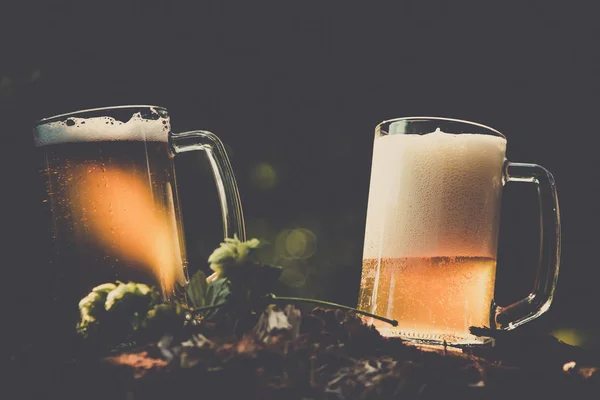 Duas canecas de cerveja leve com hop contra fundo de árvores verdes ao ar livre — Fotografia de Stock