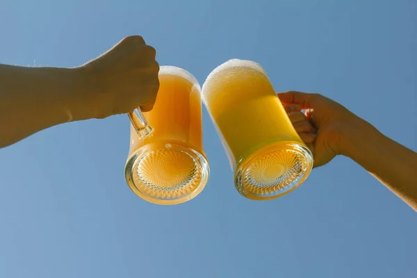 toasting with beers against clear blue sky