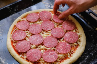 Taze İtalyan çiğ pizzası, geleneksel usulde fırında pişirme tepsisi üzerinde hazırlanma.