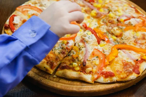 Tahta arka planda pizza yiyen bir çocuk. Bir dilim pizza.