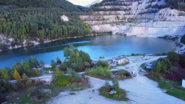  Bir yol, evler ve ağaçlarla çevrili eski bir taş ocağındaki turkuaz bir gölün üstünden hava manzarası. Yüksek kaliteli FullHD görüntüler