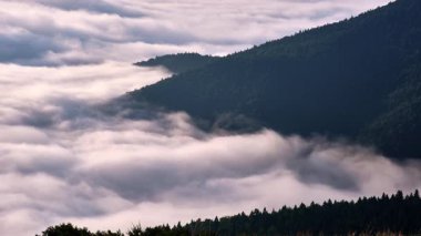 Zaman kaydına göre dağ zirvelerinin altında hareket eden sislerle dolu bir vadi var. Değişen bulut katmanı barışçıl ve gerçeküstü bir manzara yaratır..