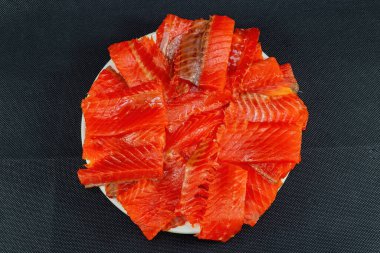 Siyah arka plan manzaralı bir tabakta dilimlenmiş alabalık. .