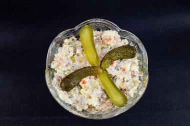 Siyah arka planda salatalıklı Olivier salatası. .