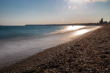 Gün batımı ve ipeksi sularla dolu bir sahil manzarası..