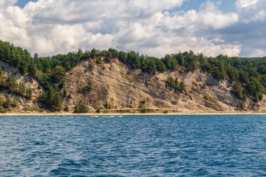 Dağlarla ve denizden gelen yeşil bitkilerle dolu bir manzara..