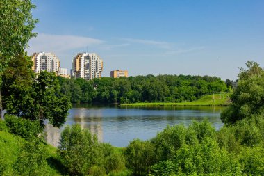 Etrafı yüksek binalar ve yeşilliklerle çevrili nehir seti..